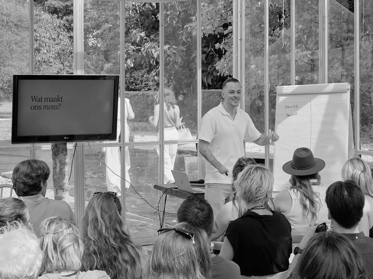 Thomas Damen spreekt lachend met het publiek naast een flip-over tijdens INSPIRE.